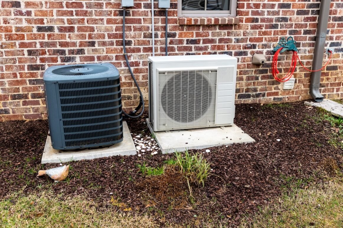 HVAC Air Conditioner Compressor and a Mini-split system together next to each other, next to a brick home.