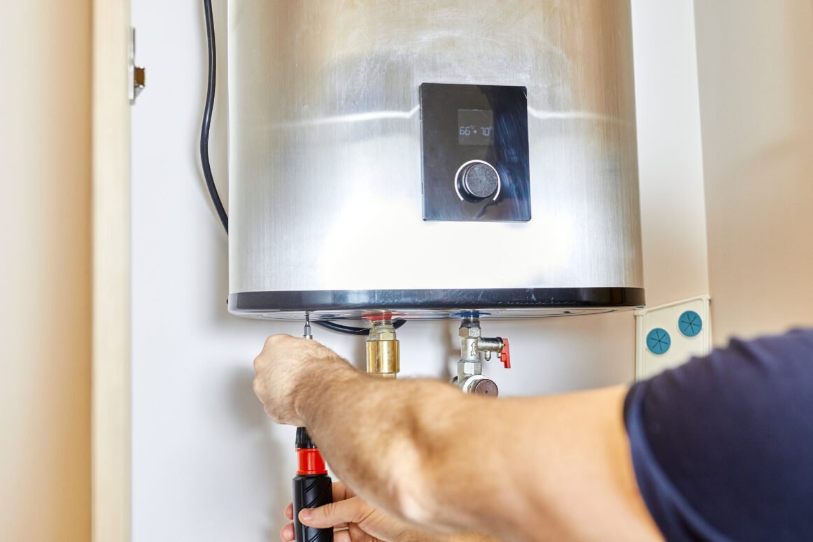 the man tightens the pipe nut in the water heating system. The master installs the water heater. The concept of bathroom maintenance. Man tightens the pipe nut in the water heating system. The master installs the water heater. The concept of bathroom maintenance.