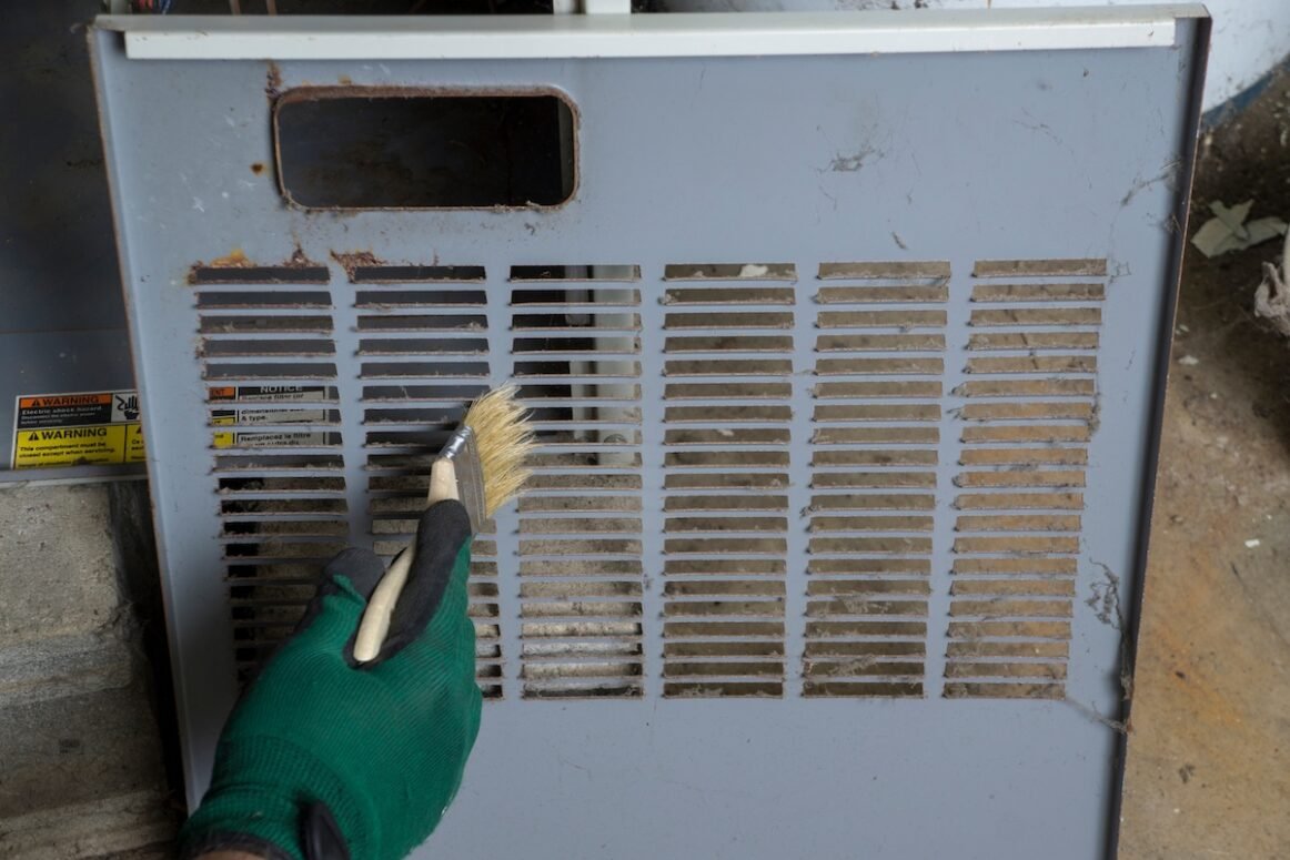 what size furnace do I need Technician cleaning the front cover os a gas furnace before re-installing .