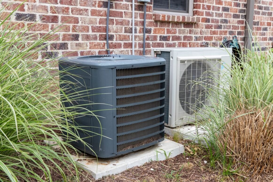 heat pump maintenance unit outside house behind brick wall