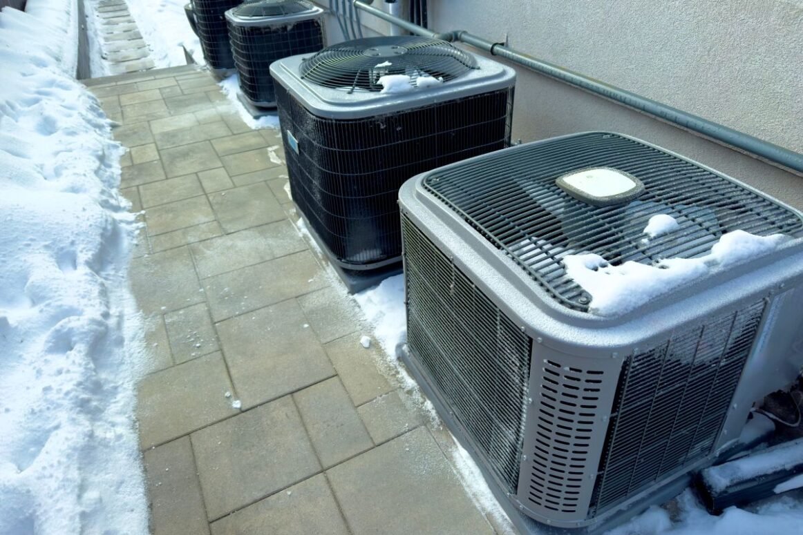 heat pump maintenance units outside house with ice and snow